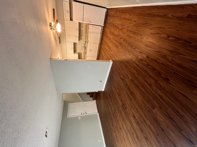 4906 West Gate Boulevard, Unit 104 Austin, TX 78745 - Photo 2 of 22 Unfurnished living room with a textured ceiling, dark wood-style floors, a ceiling fan, and stairway
