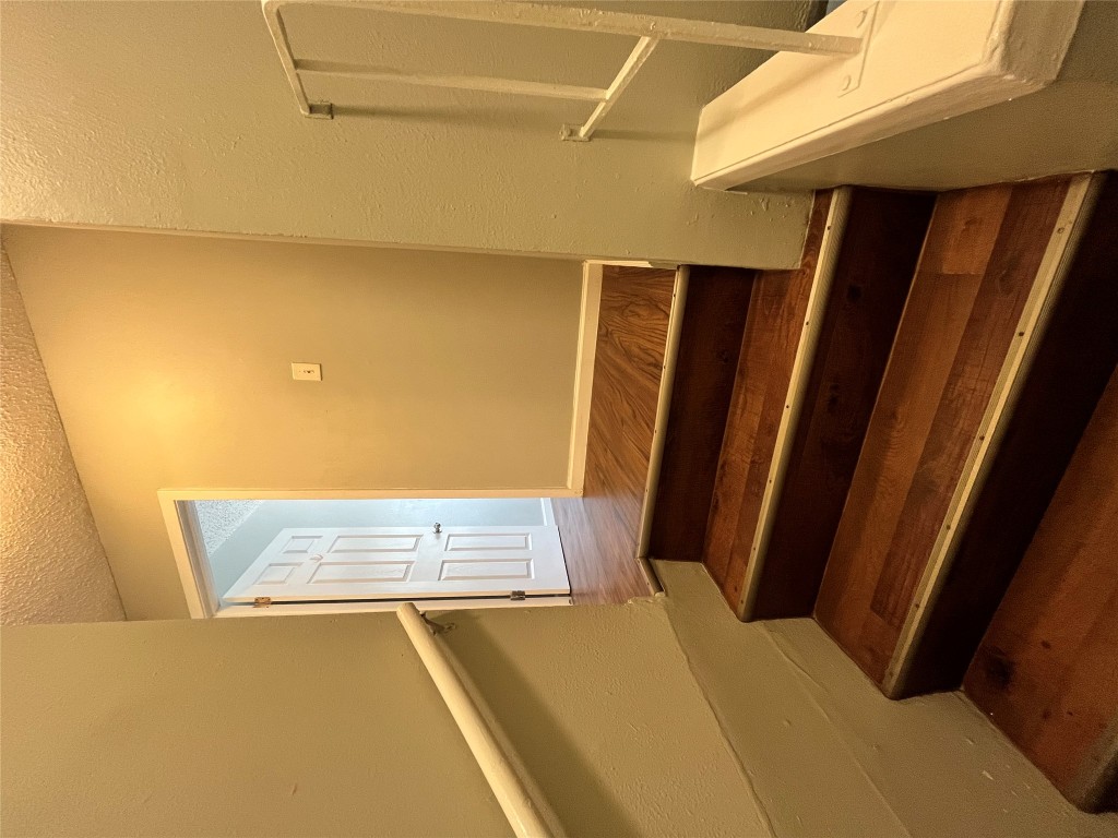 4906 West Gate Boulevard, Unit 104 Austin, TX 78745 - Photo 6 of 22 Stairs with a textured wall, a textured ceiling, and wood finished floors