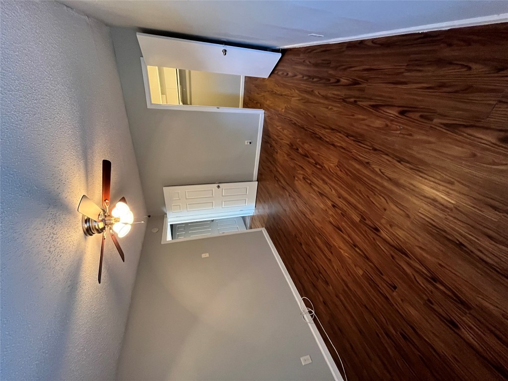 4906 West Gate Boulevard, Unit 104 Austin, TX 78745 - Photo 9 of 22 Unfurnished bedroom featuring dark wood-style floors, a textured ceiling, a walk in closet, and a ceiling fan