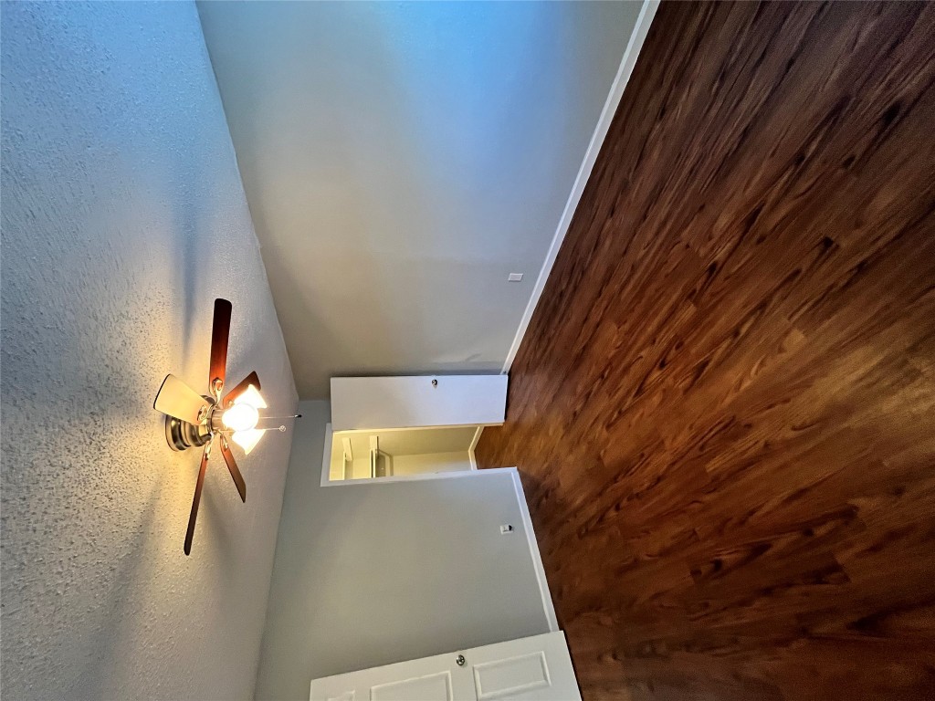 4906 West Gate Boulevard, Unit 104 Austin, TX 78745 - Photo 10 of 22 Unfurnished bedroom with a textured ceiling, dark wood finished floors, a spacious closet, and ceiling fan