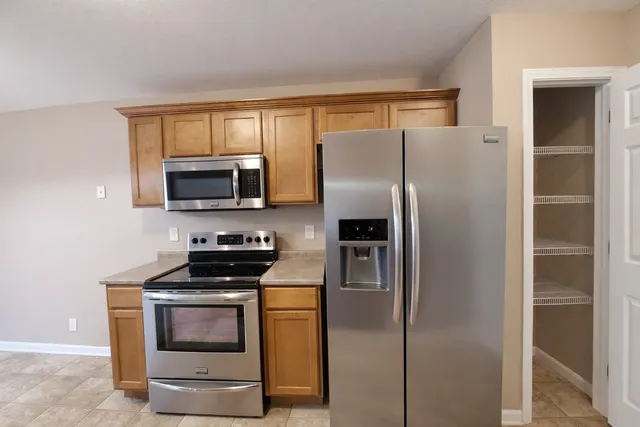 a kitchen with stainless steel appliances granite countertop a refrigerator and a stove top oven