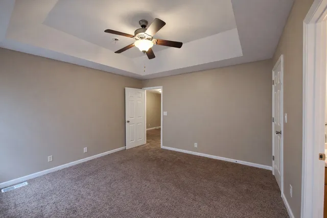 an empty room with a chandelier fan and a ceiling fan