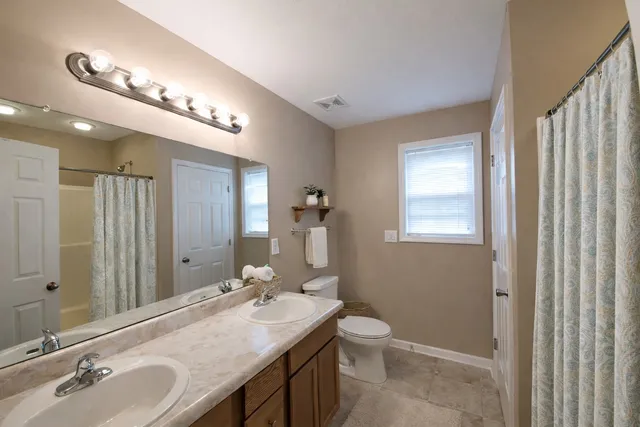 a bathroom with a granite countertop sink a toilet and a mirror