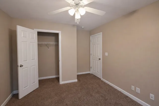 an empty room with a chandelier fan and windows