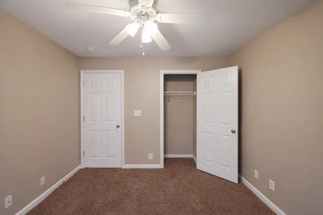 an empty room with a fan and a chandelier fan