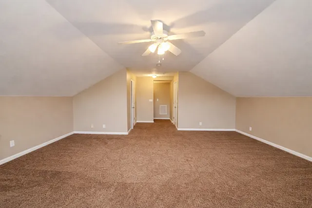 an empty room with a chandelier fan and windows