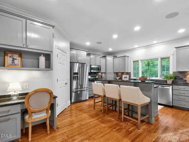 a kitchen with stainless steel appliances granite countertop a dining table chairs stove refrigerator and cabinets