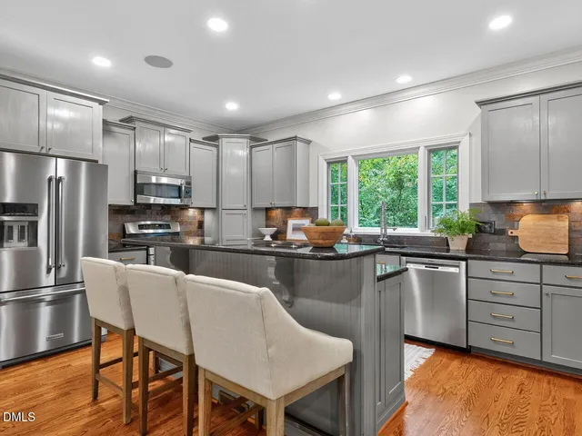 a kitchen with granite countertop a center island stainless steel appliances cabinets and a window