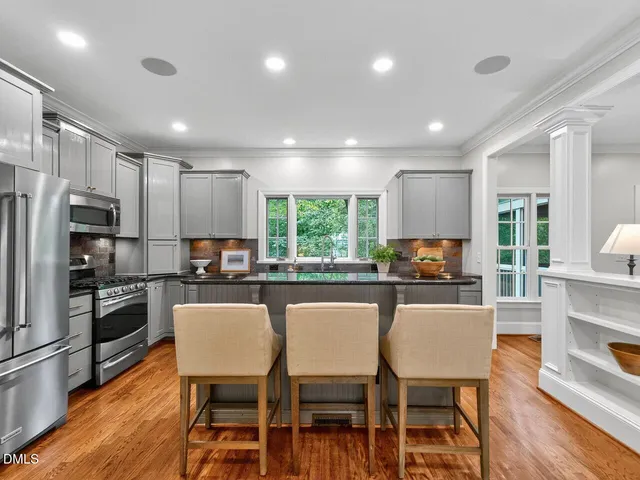 a kitchen with microwave a refrigerator and chairs