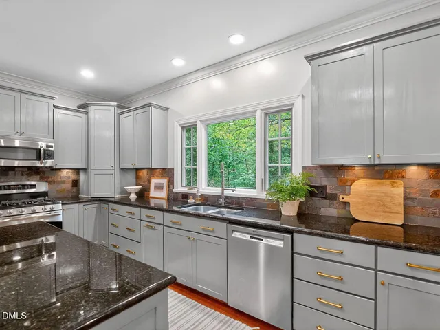 a kitchen with kitchen island granite countertop a sink stainless steel appliances and cabinets