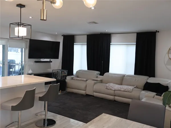 a living room with stainless steel appliances kitchen island granite countertop furniture a rug and a wooden floor