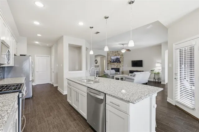 a open kitchen with center island wooden floor and stainless steel appliances