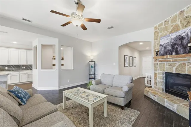 a living room with furniture a fireplace and a ceiling fan