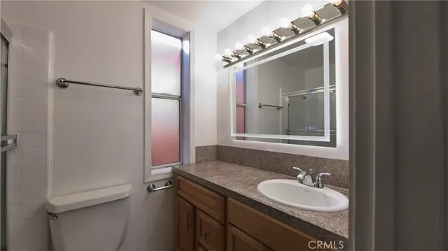 a bathroom with a granite countertop sink toilet and mirror