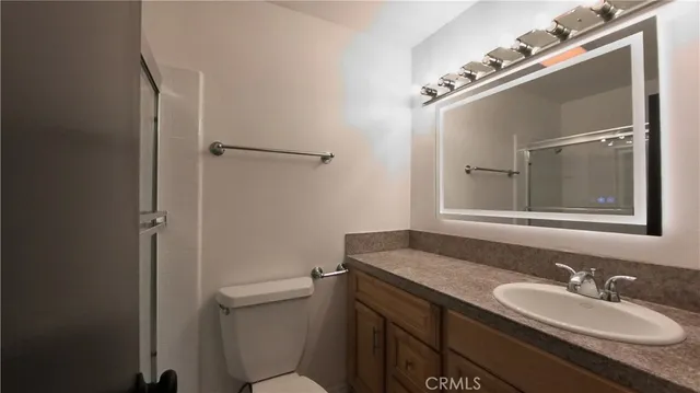 a bathroom with a granite countertop sink toilet and mirror