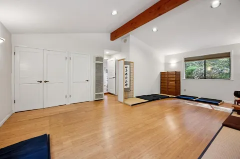 a view of an empty room with wooden floor and window