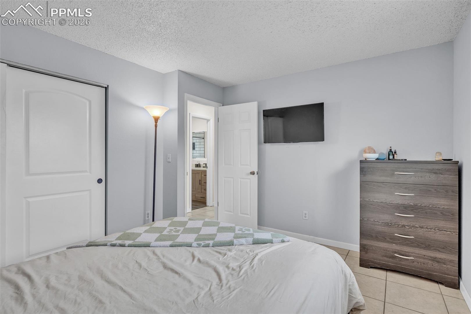 1498 Peterson Road Colorado Springs, CO 80915 - Photo 29 of 44 Bedroom with a textured ceiling, light tile patterned floors, and a closet
