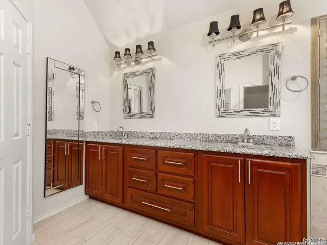 a bathroom with a granite countertop sink and a mirror