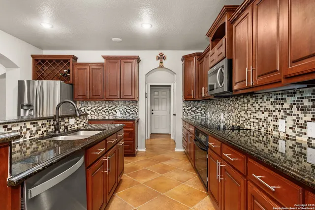 a kitchen with granite countertop stainless steel appliances a sink stove top oven and cabinets