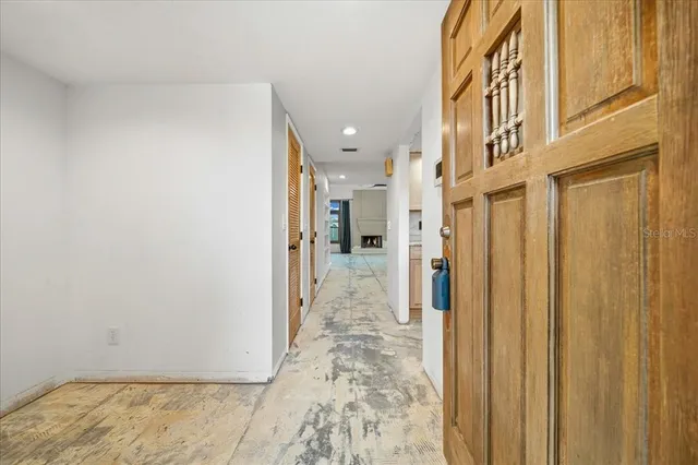 a view of a hallway with wooden floor and a bathroom