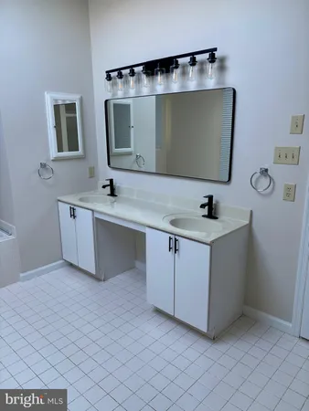 a bathroom with a double vanity sink mirror and bathtub