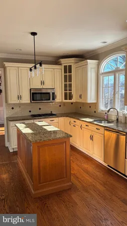 a large kitchen with stainless steel appliances granite countertop a stove a sink and a microwave