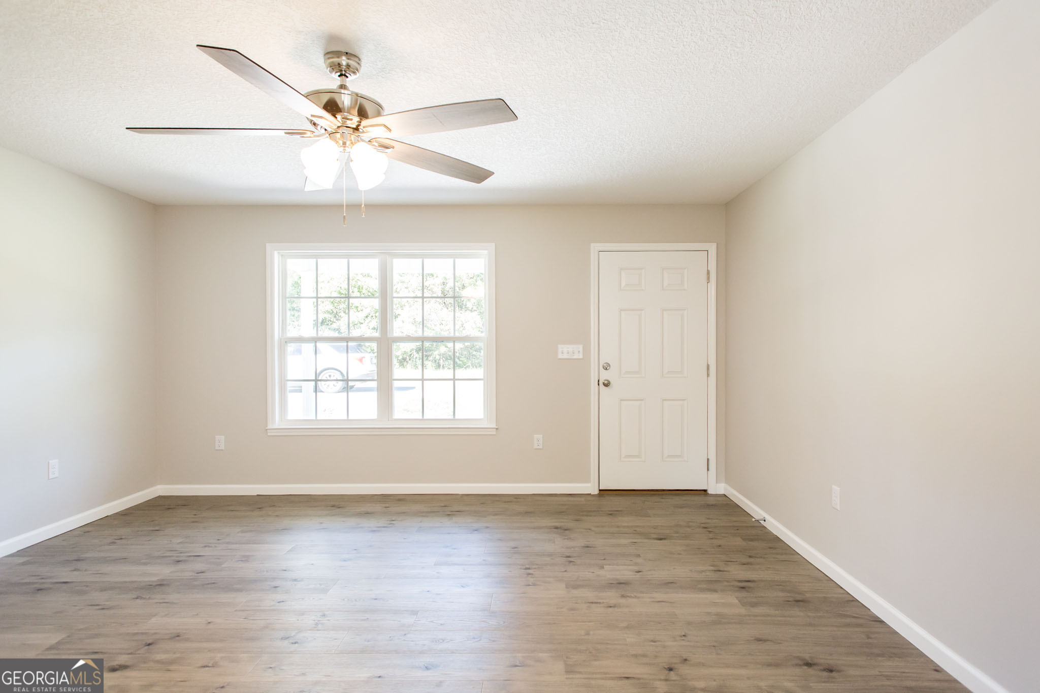 2350 Edgewood Street Waycross, GA 31501 - Photo 5 of 27 an empty room with wooden floor fan and windows