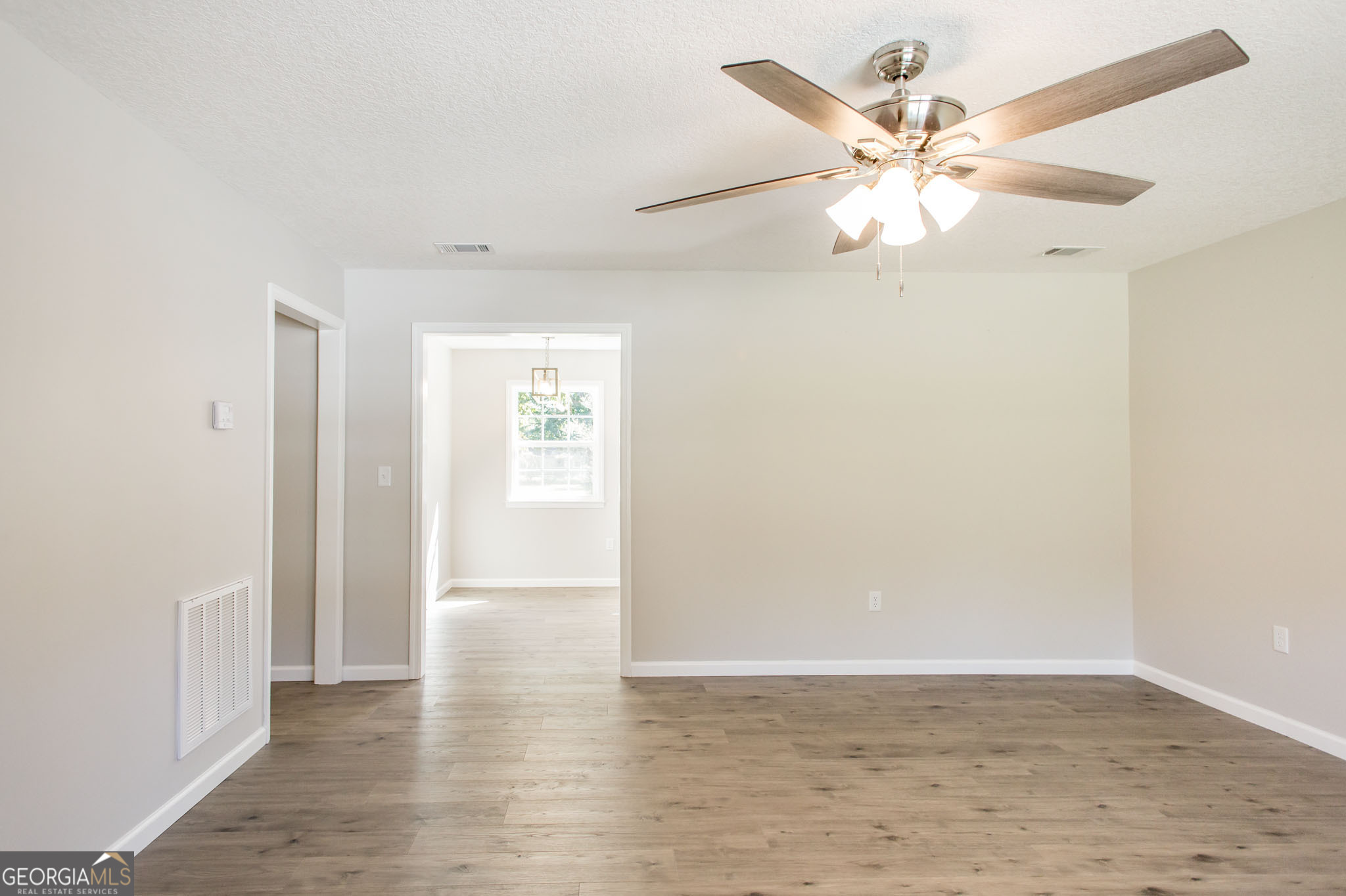 2350 Edgewood Street Waycross, GA 31501 - Photo 7 of 27 an empty room with wooden floor fan and windows