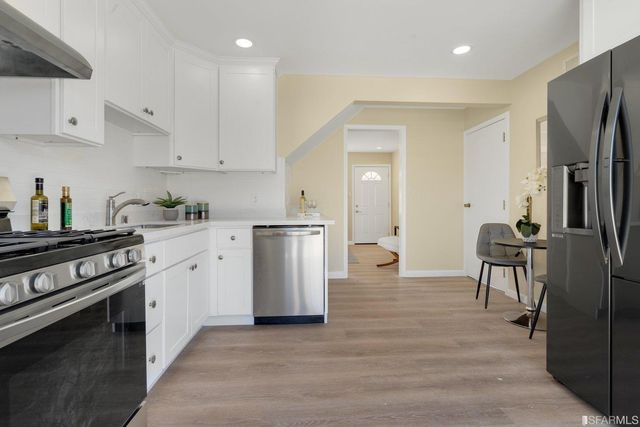 a kitchen with white cabinets and stainless steel appliances