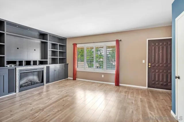 an empty room with wooden floor cabinet and windows