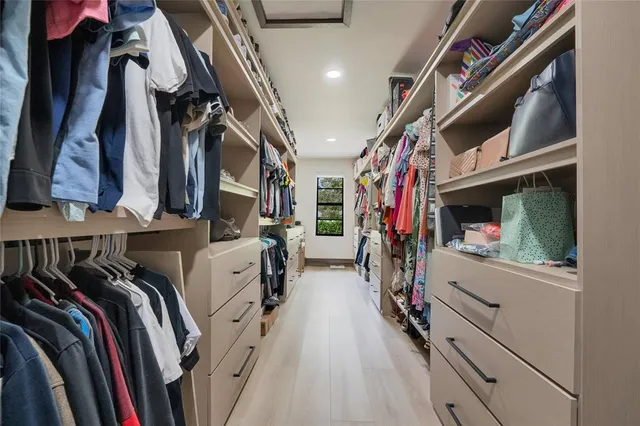 a view of walk in closet with clothes and shoes
