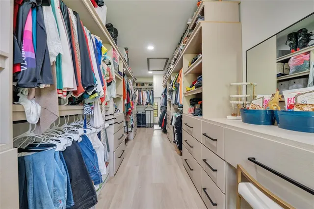 a view of walk in closet with clothes and shoes