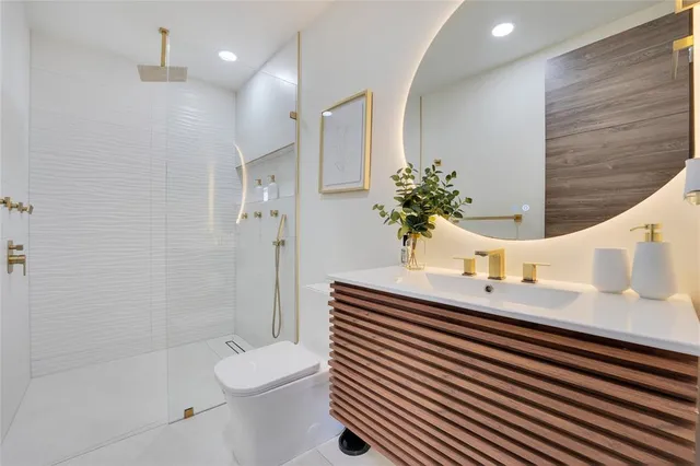 a bathroom with a sink a toilet a shower and a mirror