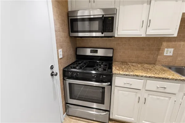 a kitchen with granite countertop white cabinets and stainless steel appliances
