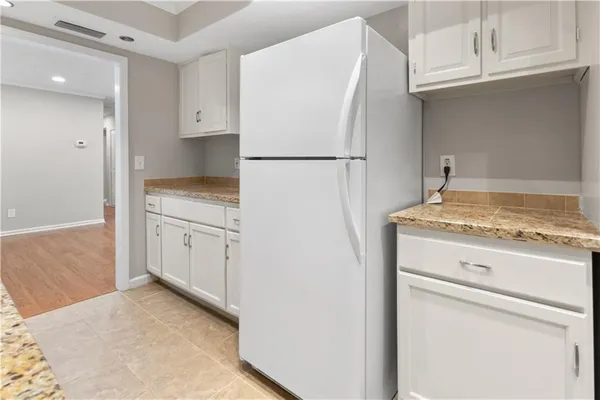 a kitchen with white cabinets and refrigerator
