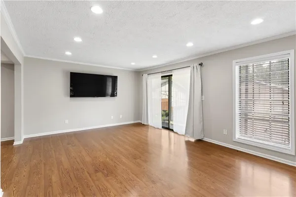 a view of an empty room with wooden floor and windows