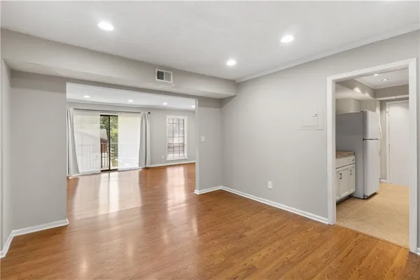 a view of an empty room with wooden floor and a window