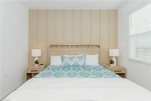 a bedroom with a large bed and a lamp on dresser