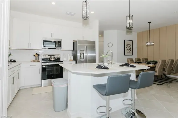 a kitchen with stainless steel appliances a stove a sink a dining table and chairs