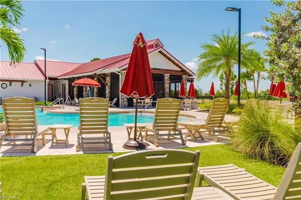 a view of a swimming pool with a lawn chairs under an umbrella with palm trees