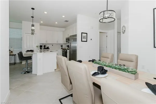 a kitchen with stainless steel appliances kitchen island granite countertop a table chairs stove and white cabinets