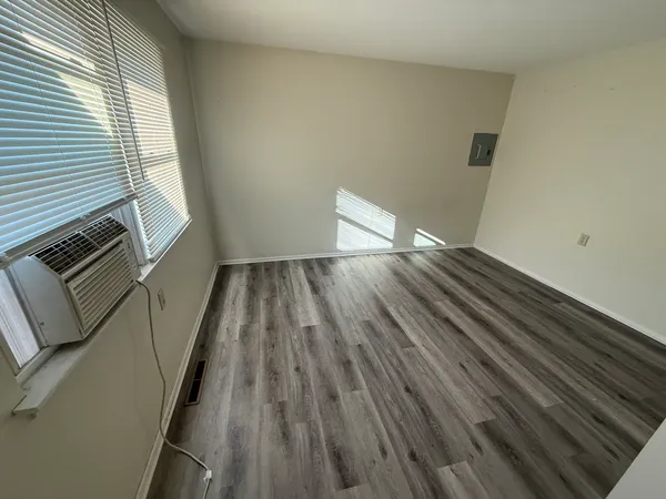 a view of an empty room with wooden floor and a window