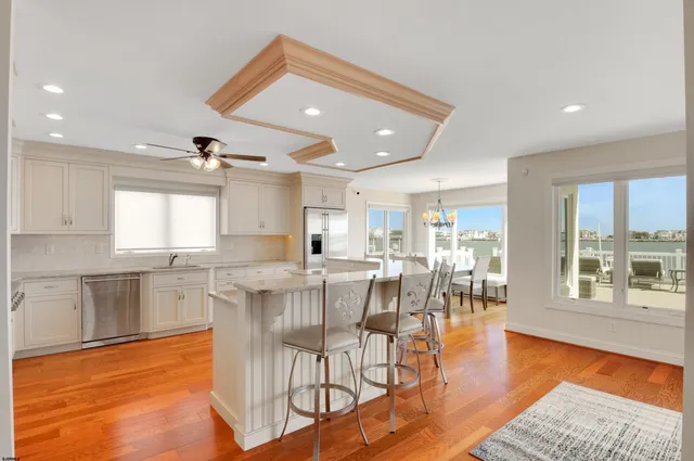 a dining hall with stainless steel appliances granite countertop a stove top oven a dining table and chairs with wooden floor