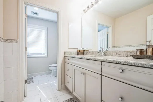 a bathroom with a granite countertop sink a toilet and a mirror