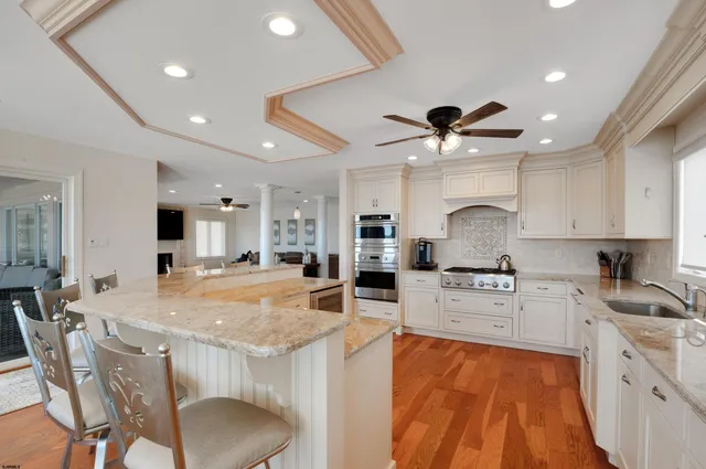 a large kitchen with stainless steel appliances granite countertop a sink dishwasher a stove a dining table and chairs with wooden floor