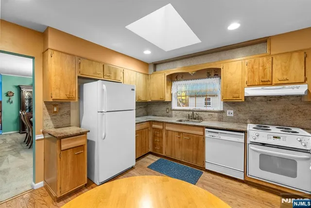 a kitchen with granite countertop stainless steel appliances a refrigerator a sink and cabinets