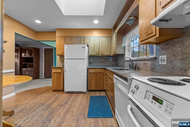 a kitchen with a refrigerator a stove and wooden floor