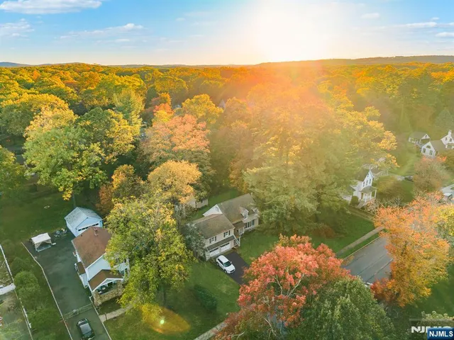 an aerial view of a house with a yard lake and trees all around