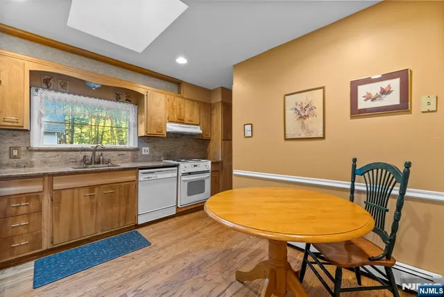 a kitchen with stainless steel appliances granite countertop a kitchen island a stove a sink a dining table and chairs