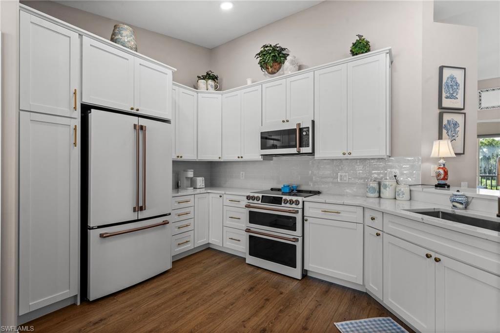 9331 Spring Run Boulevard, Unit 3005 Estero, FL 34135 - Photo 3 of 48 Kitchen featuring white shaker-style cabinetry, a built-in double oven, wood-finish flooring, a stainless steel sink, and light-toned countertops